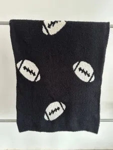 Primo piano dettagliato della coperta in pile nera con motivo jacquard palla da rugby.