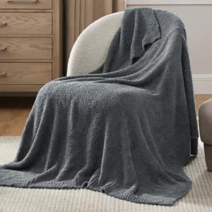 Dark grey knitted throw blanket detail showcasing soft texture and cozy winter sofa setting.