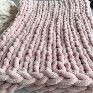 Close-up detail of soft pink chunky chenille knitted blanket, cozy handmade texture fabric.