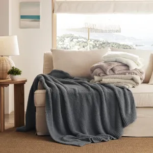 Cozy knit throw blanket draped on sofa, soft textured plush fabric for winter warmth and home decor.