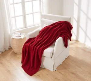 Cozy red knitted blanket draped on white armchair for home decor and warm winter living room details.