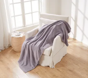 Cozy plush knitted sofa blanket in soft light purple, warm winter throw for home decor details.