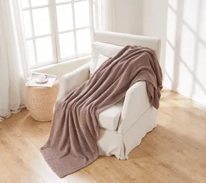 Cozy knitted throw blanket draped over a cozy living room armchair in soft brown texture.