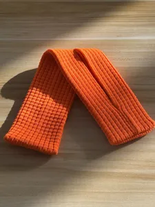 Orange knitted long phone strap detail view, soft ribbed texture accessory for daily styling.