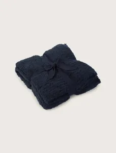 Close-up detail of folded navy blue plush blanket with ribbon tie, soft and warm texture.