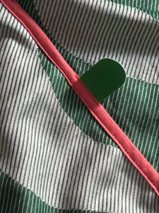 Gros plan détaillé de la texture du tissu de couverture rafraîchissante rayée avec bordure rouge.