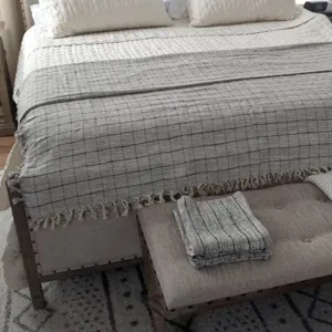 Cozy woven cotton throw blanket with plaid pattern and chic fringe detail, perfect for bed.