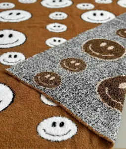 Detailed view of cozy knit jacquard smiley face throw blanket, soft plush fuzzy texture.