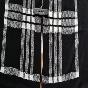 Gedetailleerd uitzicht zwart wit ruit gebreide sjaal cape bovenkleding dames winter.
