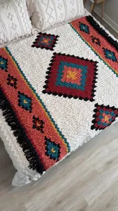 Detailed shot of ethnic boho geometric diamond knit chunky blanket with cozy tassels.