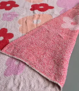 Cozy knitted plush blanket detail shot, soft feather yarn fabric with cute floral pattern.