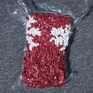 Vue detaillee de la couverture en tricot epais compressee, motif rouge et blanc sachet.
