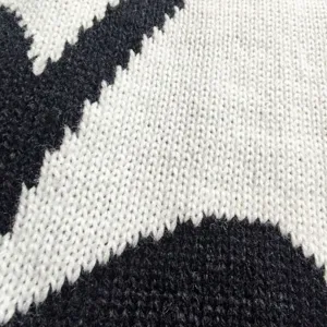 Close-up detail of women knit bat shawl fabric showing black white texture pattern.