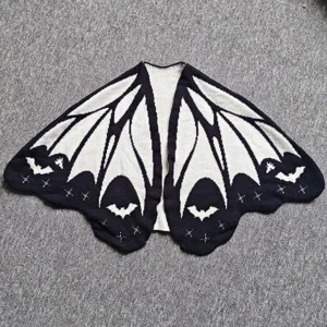 Detailed flat view of black and white bat wing knitted shawl, gothic style cardigan.