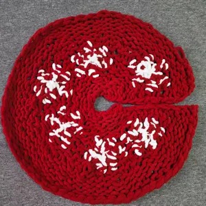Jupe de sapin de Noel tricotée rouge avec motif flocon blanc, detail de decor de vacances.