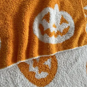Close-up of fluffy chenille blanket detail featuring a festive knit pumpkin jacquard pattern.