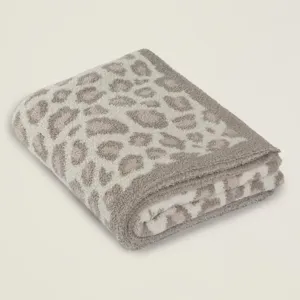 Coperta leopardata lavorata a maglia piegata, dettaglio plaid morbido in pile.