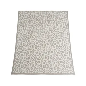 Primo piano di morbida coperta lavorata a maglia leopardata, plaid accogliente per divano.