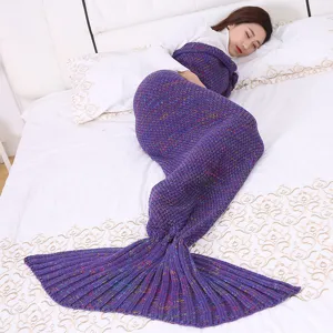 Dettaglio coperta in maglia con coda di sirena e trama viola su morbido letto.