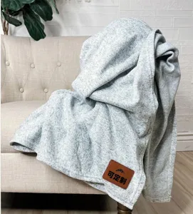 Cozy grey knitted throw blanket detail, soft textured fabric for autumn and winter warmth.