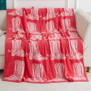 Soft knitted sofa blanket with pink cowboy boot pattern, cozy home textile detail view.