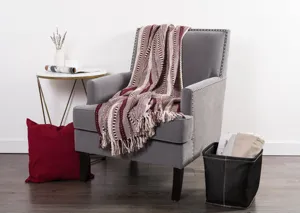Plaid tissé jacquard à franges drapé sur un fauteuil confortable dans un salon chaleureux.