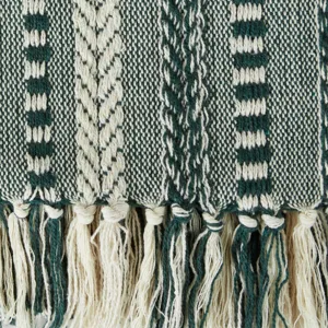 Gros plan sur les details de la couverture jacquard tissee verte et blanche a franges.
