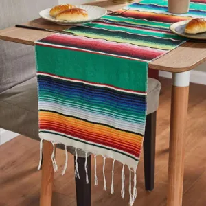 Detailed view of the colorful Mexican striped table runner with white tassels on wooden table.