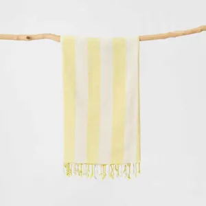 Dettaglio di telo mare in cotone a righe gialle e bianche con frange decorative.