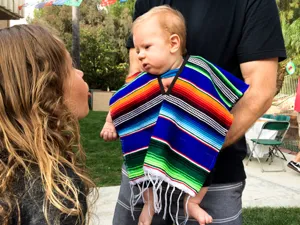 Details of the colorful Mexican serape poncho featuring vibrant rainbow stripes and cute fringe.
