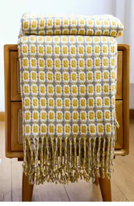 Detaillierte Ansicht der gewebten Strickdecke mit geometrischem Muster und weichen Fransen.