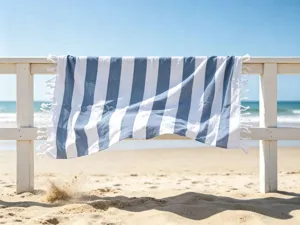 Dettaglio dell'asciugamano da spiaggia a righe blu e bianche con frange sulla staccionata.
