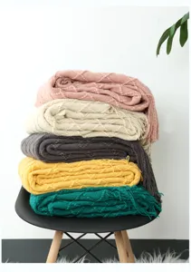 Detailansicht weicher Strickdecken mit Fransen in verschiedenen Farben auf Stuhl.