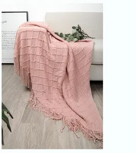 Detailaufnahme der rosa Strickdecke mit strukturiertem Karomuster und weichen Fransen.