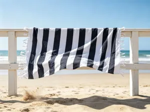 Vista dettagliata di un telo mare a righe bianco e nero appeso a una staccionata.