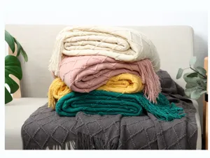 Detaillierte Ansicht bunter gestrickter Fransen-Wohndecken ordentlich gestapelt auf Sofa.