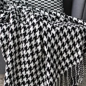 Detailansicht einer schwarz-weißen Hahnentritt-Strickdecke mit weicher Textur und Fransen.