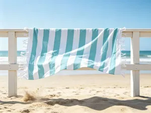 Dettaglio di un bellissimo telo mare turco a righe verde acqua e bianche su staccionata.