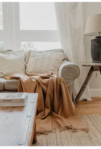 Cozy camel merino wool throw blanket displayed in a warm, elegant living room setting.