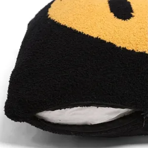 Close-up detail of black fleece cushion cover with yellow smiley design and zipper.