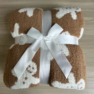 Gingerbread man patterned fleece blanket detail shot, soft plush texture with elegant white ribbon.