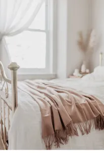 Cozy merino wool throw blanket detail featuring soft fringe and warm taupe aesthetic color.