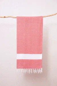 Detailopname van een prachtig geweven Turkse strandhanddoek met rode patronen en franjes.