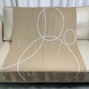 Beige knitted throw blanket with modern white geometric circle pattern for cozy sofa living room decor.