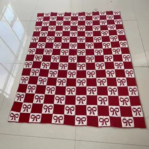 Red and white checkered knit blanket with cute bow patterns, cozy winter home decor.