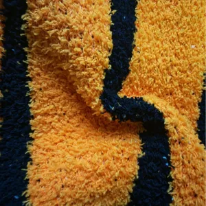 Orange and black striped plush velvet blanket fabric close-up soft cozy warm textile.