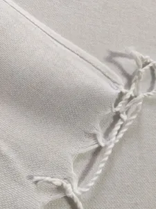 Detailed view of white woven Turkish beach towel featuring delicate fringe and soft texture.
