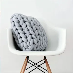 Close-up detail shot of a cozy grey chunky knit round decorative throw pillow on a chair.