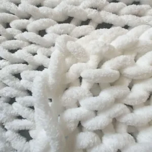 Close-up view of white chunky knit chenille blanket texture, soft fluffy handmade yarn detail.