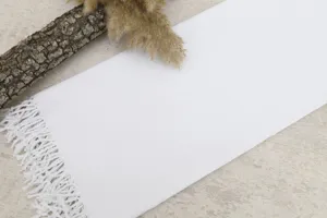 Close-up view of a soft white Turkish beach towel featuring delicate braided fringe.